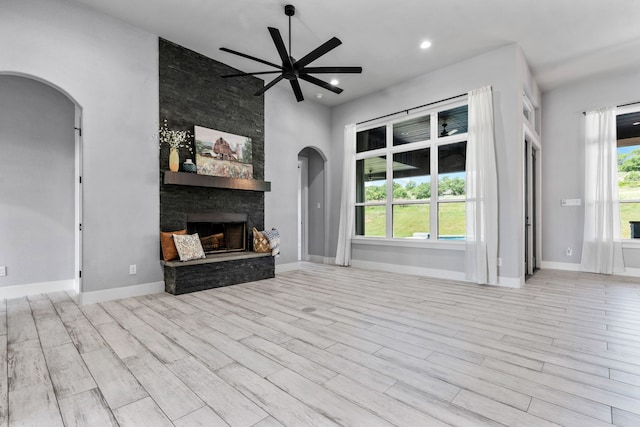 521 Echo Glade Ct, Azle, TX 76020 - unfurnished living room with arched walkways, ceiling fan, a stone fireplace, wood finished floors, and recessed lighting