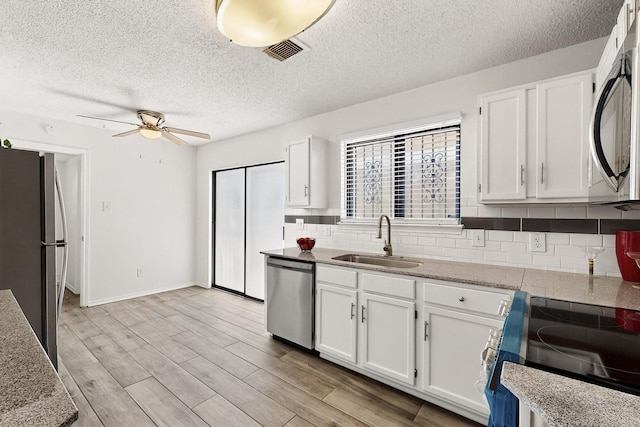 10320 Wood Heights Dr, Dallas, TX 75227 - kitchen featuring stainless steel appliances, decorative backsplash, white cabinetry, a ceiling fan, and a textured ceiling