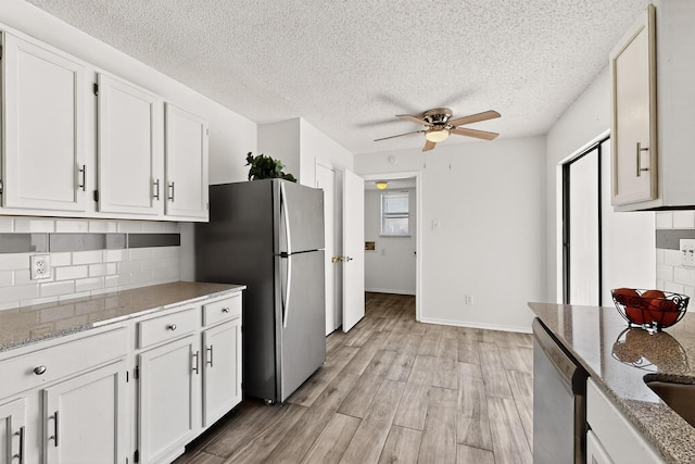 10320 Wood Heights Dr, Dallas, TX 75227 - kitchen with appliances with stainless steel finishes, decorative backsplash, a ceiling fan, white cabinetry, and a textured ceiling
