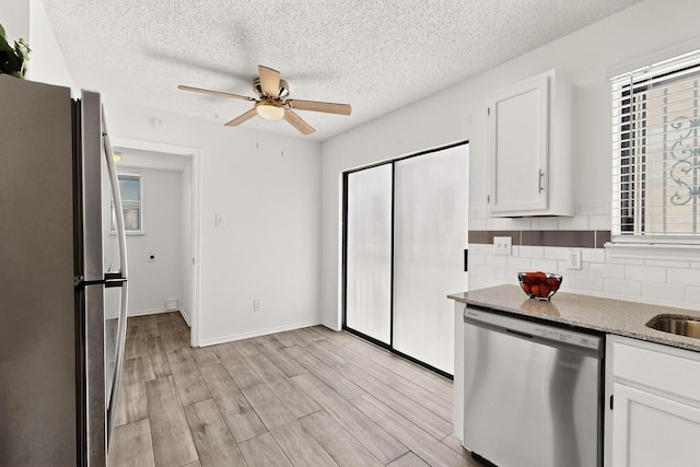 10320 Wood Heights Dr, Dallas, TX 75227 - kitchen with appliances with stainless steel finishes, a ceiling fan, a textured ceiling, white cabinets, and backsplash
