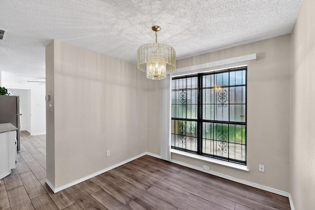 10320 Wood Heights Dr, Dallas, TX 75227 - unfurnished dining area with a chandelier, a textured ceiling, and wood finished floors