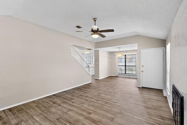 10320 Wood Heights Dr, Dallas, TX 75227 - unfurnished living room featuring ceiling fan, lofted ceiling, wood finished floors, a textured ceiling, and stairs