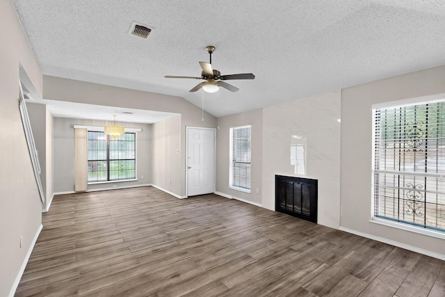 10320 Wood Heights Dr, Dallas, TX 75227 - unfurnished living room featuring wood finished floors, a fireplace, vaulted ceiling, a textured ceiling, and ceiling fan