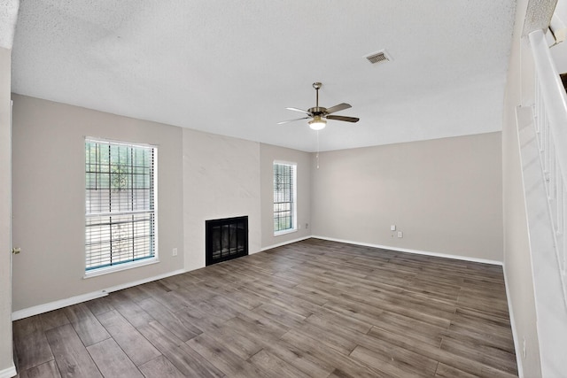 10320 Wood Heights Dr, Dallas, TX 75227 - unfurnished living room with ceiling fan, healthy amount of natural light, wood finished floors, a glass covered fireplace, and a textured ceiling