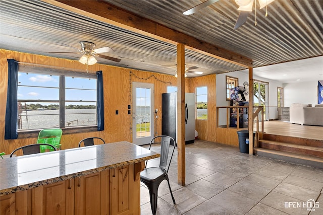 894 W Moonshine Rd, Seymour, TX 76380 - kitchen with a ceiling fan, wooden walls, freestanding refrigerator, and healthy amount of natural light