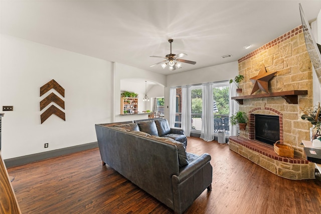 1740 Greenwood Ct, Prosper, TX 75078 - living room featuring dark wood-type flooring, a stone fireplace, a ceiling fan, and arched walkways