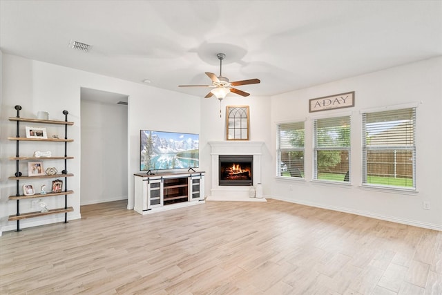 813 Evergreen St, Princeton, TX 75407 - unfurnished living room featuring light wood-style floors, a warm lit fireplace, and a ceiling fan