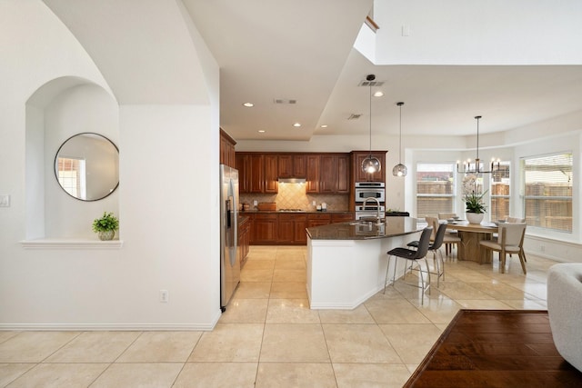 1205 Apache Lake Dr, Carrollton, TX 75010 - kitchen featuring dark countertops, light tile patterned floors, a breakfast bar area, decorative backsplash, and a kitchen island with sink