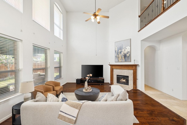 1205 Apache Lake Dr, Carrollton, TX 75010 - living area with a tile fireplace, a ceiling fan, a high ceiling, arched walkways, and wood finished floors