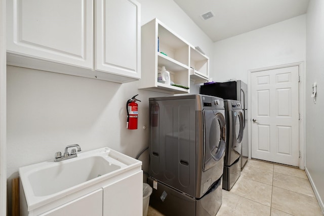 1205 Apache Lake Dr, Carrollton, TX 75010 - laundry area featuring washer and dryer, cabinet space, and light tile patterned flooring