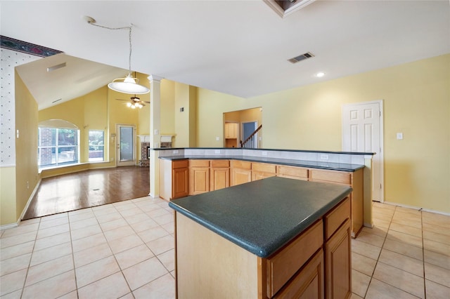 8201 Fountain Ridge Dr, Plano, TX 75025 - kitchen featuring dark countertops, a center island, light tile patterned flooring, open floor plan, and lofted ceiling