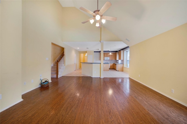 8201 Fountain Ridge Dr, Plano, TX 75025 - unfurnished living room featuring light wood-style floors, ceiling fan, stairway, and high vaulted ceiling