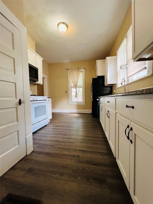 106 Lawrence Ave, Terrell, TX 75160 - kitchen with gas range gas stove, stainless steel microwave, white cabinetry, and dark wood finished floors