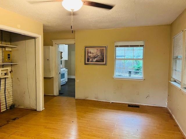 106 Lawrence Ave, Terrell, TX 75160 - unfurnished bedroom featuring wood finished floors, a textured ceiling, freestanding refrigerator, connected bathroom, and a closet