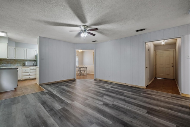 6179 State Highway 31 E, Murchison, TX 75778 - unfurnished living room with a ceiling fan, wood finished floors, and a textured ceiling
