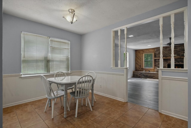 6179 State Highway 31 E, Murchison, TX 75778 - dining room featuring a textured ceiling, wooden walls, tile patterned flooring, and a wainscoted wall