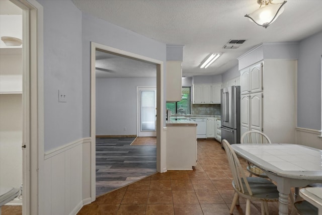 6179 State Highway 31 E, Murchison, TX 75778 - kitchen featuring high quality fridge, white cabinetry, tile counters, white dishwasher, and dark tile patterned flooring