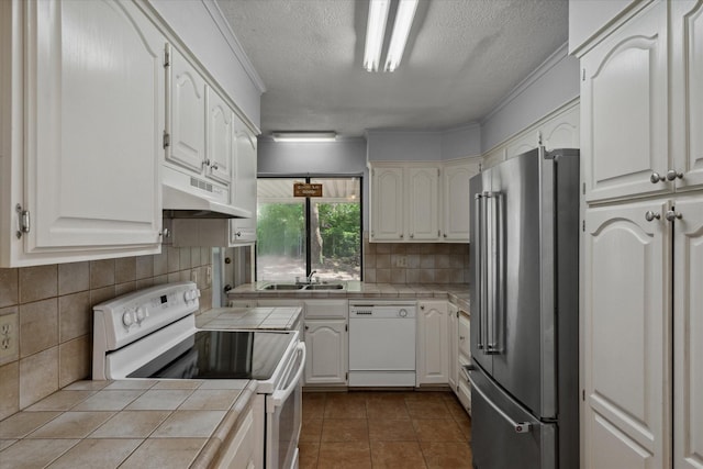 6179 State Highway 31 E, Murchison, TX 75778 - kitchen featuring white appliances, tile counters, under cabinet range hood, a textured ceiling, and decorative backsplash
