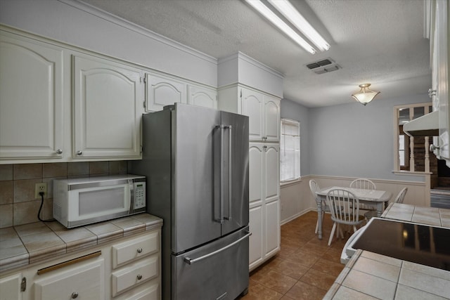 6179 State Highway 31 E, Murchison, TX 75778 - kitchen featuring white appliances, tile countertops, a textured ceiling, backsplash, and tile patterned floors