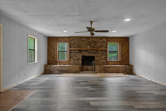 6179 State Highway 31 E, Murchison, TX 75778 - unfurnished living room featuring wood finished floors, ceiling fan, a brick fireplace, a textured ceiling, and wooden walls