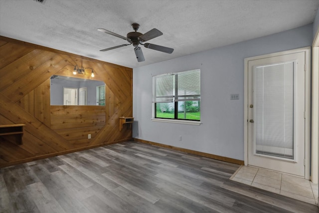 6179 State Highway 31 E, Murchison, TX 75778 - unfurnished living room featuring wooden walls, wood finished floors, a ceiling fan, and a textured ceiling