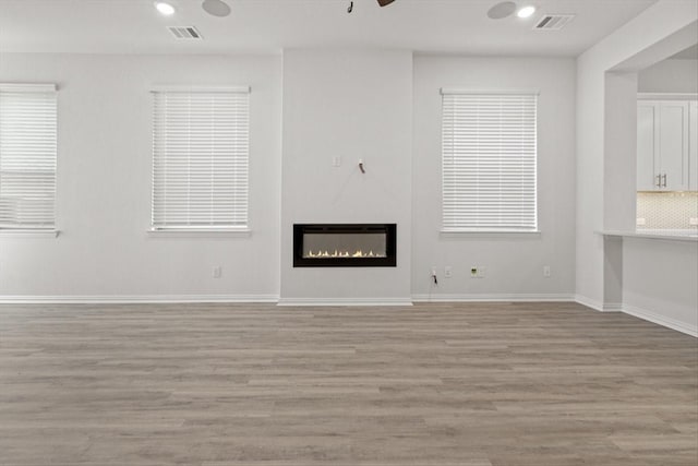 2105 Hazel Lily Run, Mesquite, TX 75181 - unfurnished living room with light wood finished floors, a glass covered fireplace, and recessed lighting