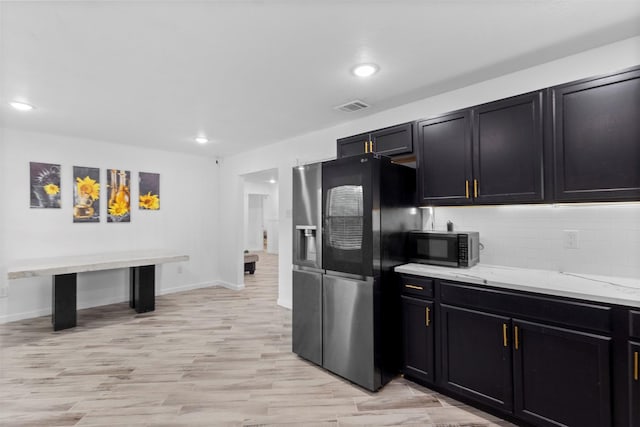 1035 Warden St, Benbrook, TX 76126 - kitchen featuring refrigerator with ice dispenser, black microwave, decorative backsplash, light wood-style floors, and recessed lighting