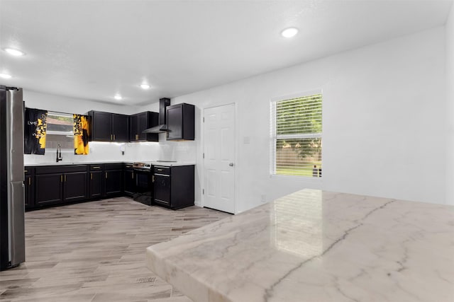 1035 Warden St, Benbrook, TX 76126 - kitchen with range with electric cooktop, wall chimney exhaust hood, recessed lighting, healthy amount of natural light, and light stone countertops