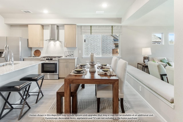 937 Kingbird Ln, Alvarado, TX 76009 - kitchen featuring stainless steel gas range, wall chimney exhaust hood, freestanding refrigerator, light wood-style floors, and decorative backsplash