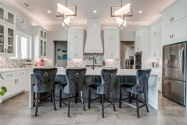 720 Glade Park Ct, Azle, TX 76020 - kitchen with stainless steel appliances, premium range hood, a center island with sink, crown molding, and light countertops