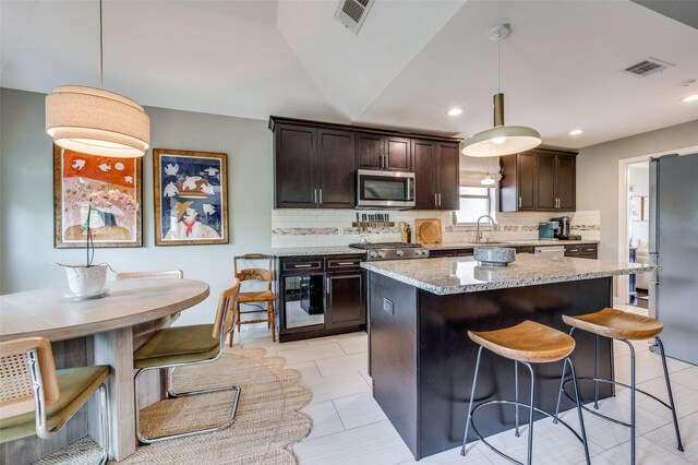 9126 Valley Chapel Ln, Dallas, TX 75220 - kitchen featuring appliances with stainless steel finishes, backsplash, dark brown cabinets, a kitchen island, and recessed lighting