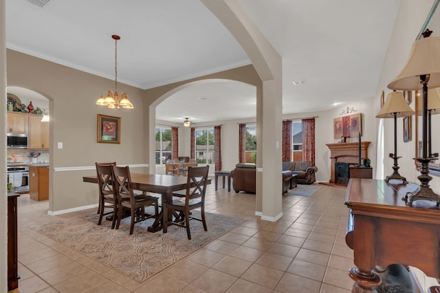 5233 Scenic Point Dr, Fort Worth, TX 76244 - dining space with light tile patterned floors, arched walkways, a fireplace with raised hearth, a chandelier, and crown molding