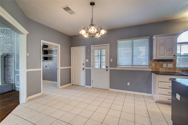 1015 Midnight Pass, Rockwall, TX 75087 - kitchen with dark countertops, a chandelier, hanging light fixtures, tasteful backsplash, and light tile patterned floors