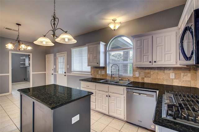 1015 Midnight Pass, Rockwall, TX 75087 - kitchen with stainless steel appliances, light tile patterned floors, a kitchen island, decorative backsplash, and white cabinetry