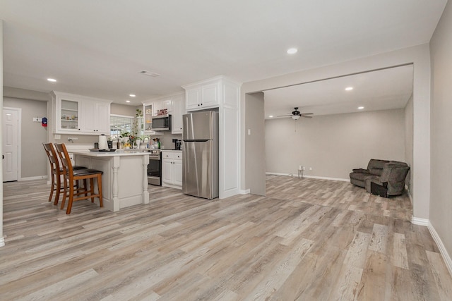 621 New Market Rd, Mesquite, TX 75149 - kitchen featuring appliances with stainless steel finishes, ceiling fan, open floor plan, a breakfast bar, and white cabinetry
