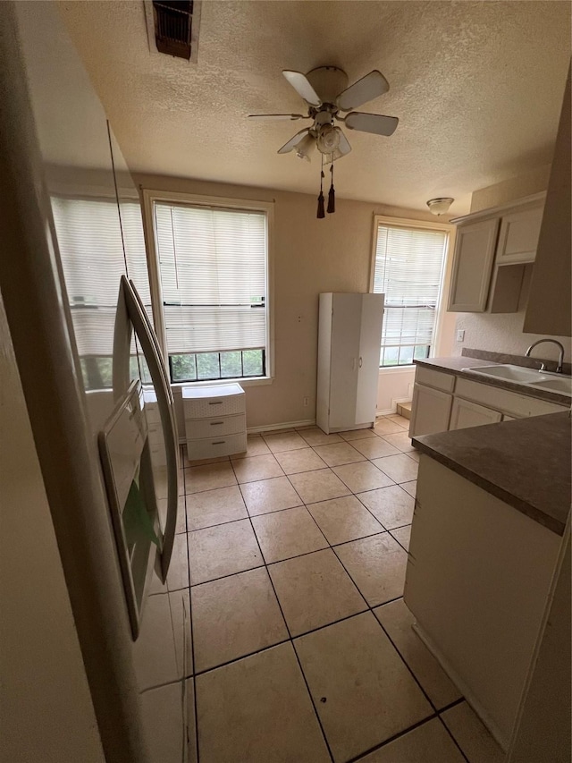 710 W Main St, Denison, TX 75020 - kitchen with a textured ceiling, plenty of natural light, a ceiling fan, light tile patterned flooring, and dark countertops