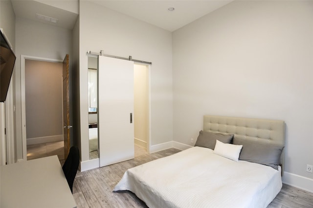 548 Oak Grove Ln, Coppell, TX 75019 - bedroom featuring light wood-style flooring and a barn door