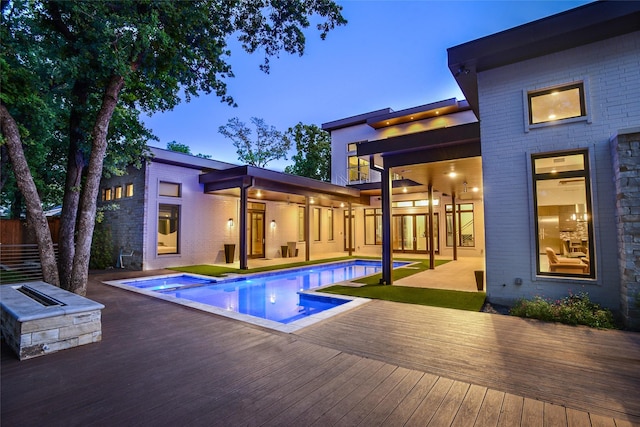 548 Oak Grove Ln, Coppell, TX 75019 - back of property at dusk featuring a wooden deck, brick siding, and a pool with connected hot tub