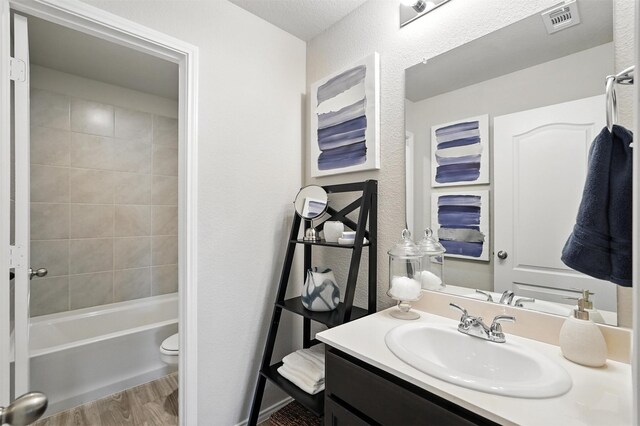 3001 Percheron Dr, Mesquite, TX 75150 - bathroom featuring vanity, wood finished floors, a textured wall, and bathtub / shower combination