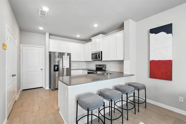 3001 Percheron Dr, Mesquite, TX 75150 - kitchen featuring stainless steel appliances, a peninsula, light wood-style flooring, white cabinetry, and recessed lighting