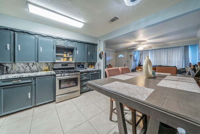 714 Macgregor Dr, Grand Prairie, TX 75050 - kitchen featuring stainless steel range with gas cooktop, backsplash, light tile patterned floors, ceiling fan, and ornamental molding