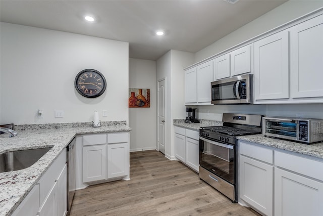 206 Marsh Ln, Princeton, TX 75407 - kitchen with appliances with stainless steel finishes, light wood-type flooring, white cabinets, light stone counters, and recessed lighting