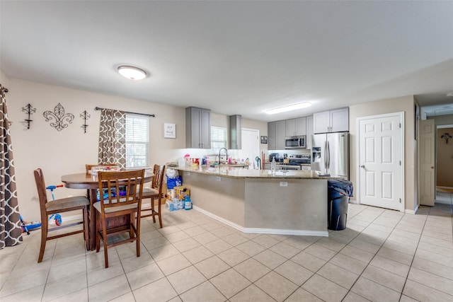 318 E Chestnut St, Denison, TX 75021 - kitchen with stainless steel appliances, a peninsula, light stone countertops, light tile patterned floors, and gray cabinets