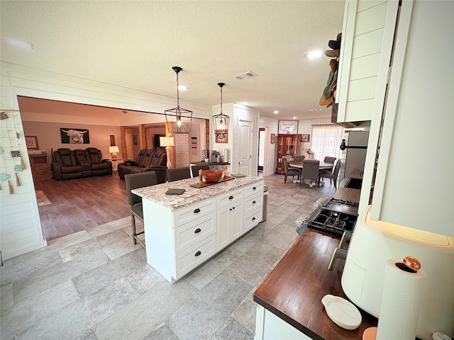 4124 Maryview Ct, Haltom City, TX 76117 - kitchen with white cabinetry, pendant lighting, a kitchen island, range with gas cooktop, and a textured ceiling