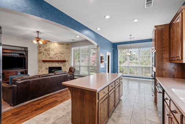 1904 Yarmouth Ct, Mansfield, TX 76063 - kitchen featuring a ceiling fan, a fireplace, light countertops, a kitchen island, and healthy amount of natural light