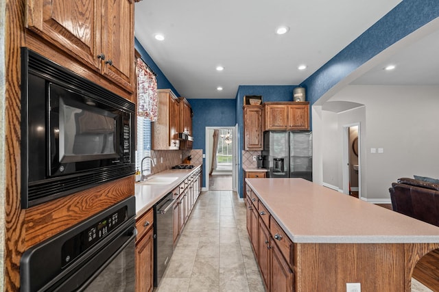 1904 Yarmouth Ct, Mansfield, TX 76063 - kitchen featuring black appliances, a center island, brown cabinets, light countertops, and backsplash
