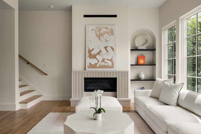 3939 Hawthorne Unit 103, Dallas, TX 75219 - living area featuring light wood-type flooring, built in features, stairway, and a glass covered fireplace