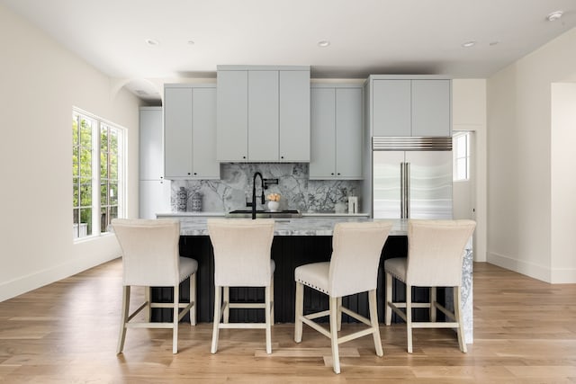 3939 Hawthorne Unit 103, Dallas, TX 75219 - kitchen featuring stainless steel built in fridge, backsplash, a center island with sink, a breakfast bar area, and recessed lighting