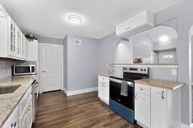 1521 Windsor Dr, Glenn Heights, TX 75154 - kitchen with appliances with stainless steel finishes, arched walkways, dark wood-type flooring, glass insert cabinets, and white cabinets