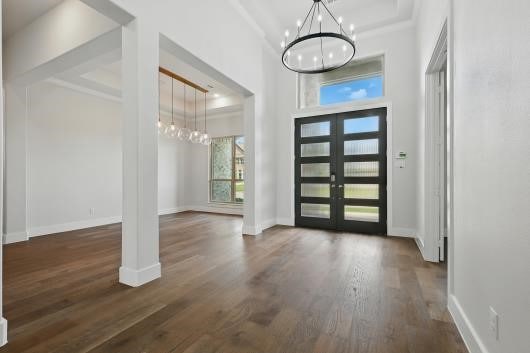 521 Winslow Ln, Prosper, TX 75078 - foyer entrance with a chandelier, a high ceiling, wood finished floors, french doors, and decorative columns